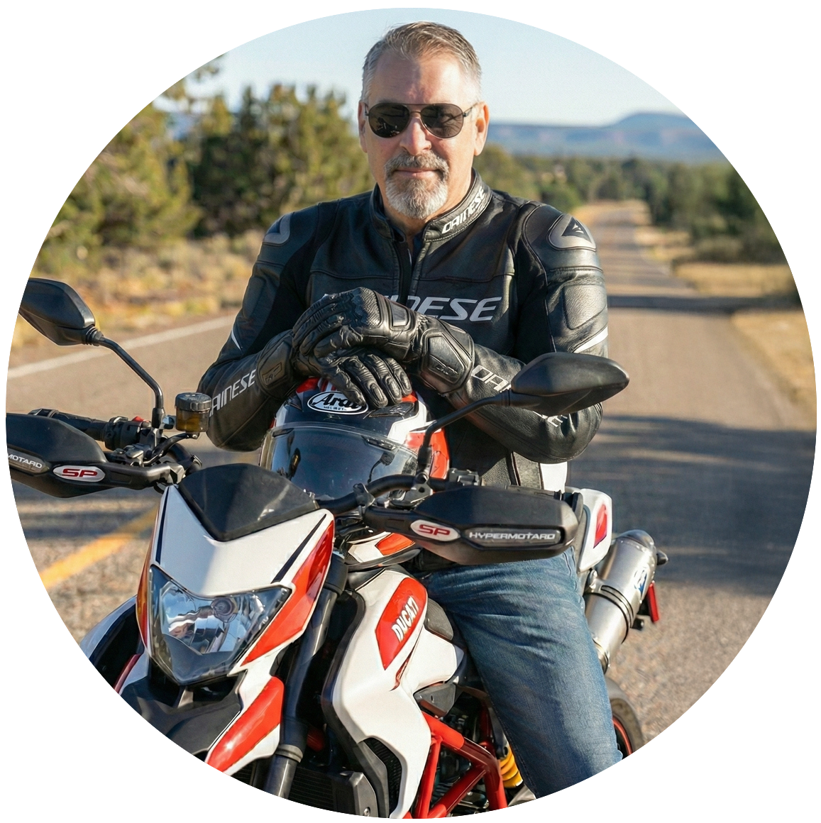 man sitting on motorcycle with helmet resting on tank