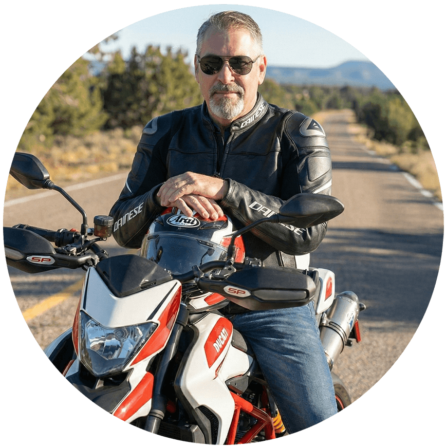 man sitting on motorcycle with helmet resting on tank